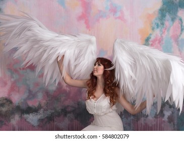 beautiful young model with open angel wings  with pink sky background