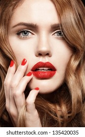 Beautiful young model with red lips and red manicure