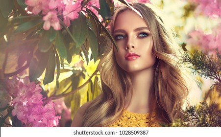 Beautiful young model spring girl   in flowers with hairstyle in summer blossom park. Woman in a blooming garden . Fashion, Cosmetics & Perfumes 
