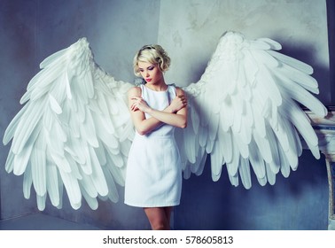 beautiful young model wearing a white dress with angel wings in the studio