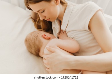 Beautiful young mom and her cute little baby sleeping in bed at home