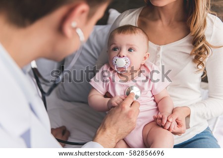 Beautiful young mom is holding her cute baby while doctor is listening to baby's lungs