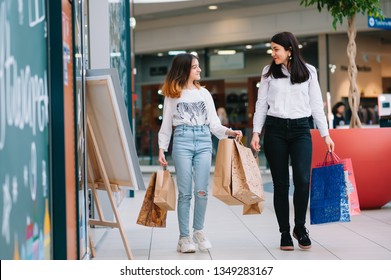 Beautiful Young Mom And Teenage Daughter Are Holding Shopping Bags, Shopping In Mall. Family Shopping.