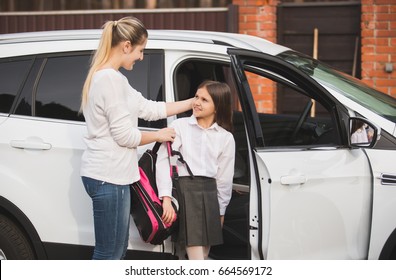 Beautiful Young Mother Helping Daughter To Get Out Of Car And Put On School Bag