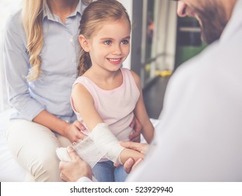 Beautiful young mother and her little daughter at the pediatrician. Doctor is bandaging little patient's arm - Powered by Shutterstock