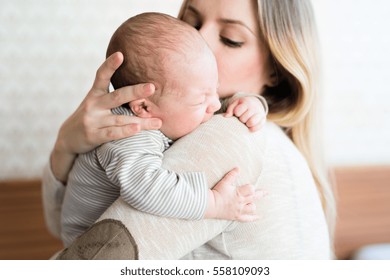 Beautiful young mother holding her baby son in her arms