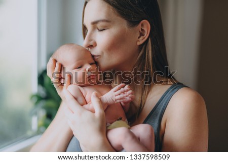 beautiful young mother holds gently her newborn baby by the home