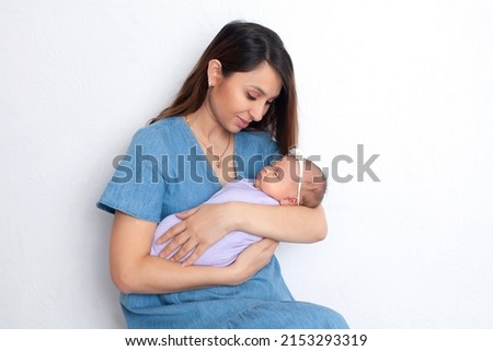 Beautiful young mother with a newborn daughter in a diaper on a white background. Motherhood. Tenderness. Space for text. High quality photo