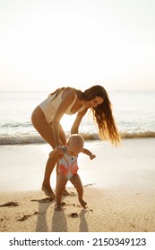 Beautiful young mother play and walk with daughter at the sea sunset and beach background. Happy family vacation. Travel. Caucasian happy female with baby outside at ocean sunset. Motherhood love care - Shutterstock ID 2150349123
