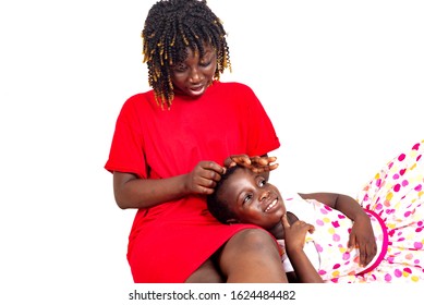 beautiful young mother sitting makes braids on the head of the little daughter at home smiling. - Powered by Shutterstock