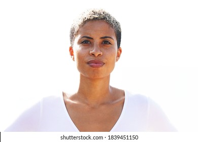 Beautiful young multicultural woman stands outside on sunny day in white shirt against white background with pleasant look on her face, short hair looking straight ahead                              - Shutterstock ID 1839451150