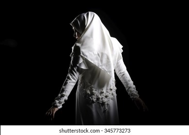 Beautiful young muslim woman bride wearing white hijab and wedding dress isolated on black background