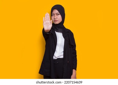 Beautiful Young Muslim Woman Hand Doing Stop Sign With Serious Expression Defense Gesture Isolated On Yellow Background
