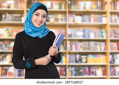 Belle jeune femme musulmane avec des cahiers sur fond bibliothèque