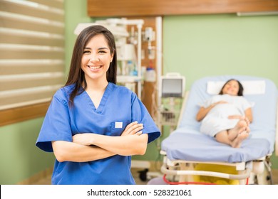 Beautiful young nurse standing with arms crossed in a hospital room with a patient