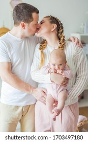 Beautiful young parents are holding their little newborn daughter in their arms. Blue-eyed little girl of 2 months. - Shutterstock ID 1703497180