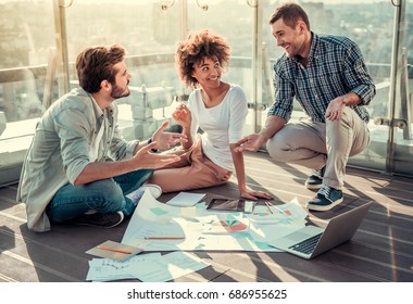 Beautiful young people are discussing projects, using gadgets and studying documents while working on balcony of the city building - Shutterstock ID 686955625