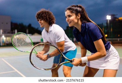 Beautiful young people are playing tennis as a team on tennis court outdoors. People sport concept - Powered by Shutterstock