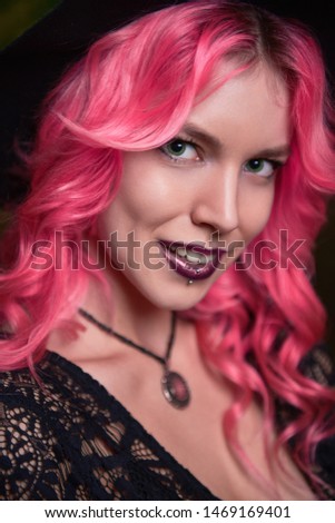 Beautiful young pink-haired witch. Close-up portrait of smiling young girl
