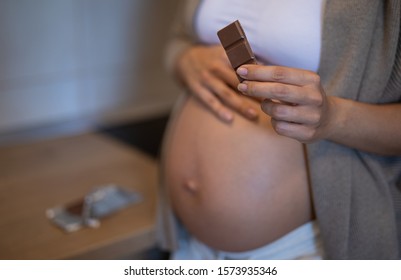 Beautiful young pregnant woman is eating chocolate - Powered by Shutterstock