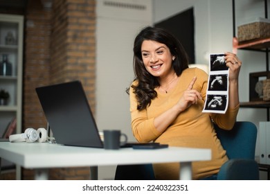 Beautiful young pregnant woman holding ultrasound pictures of her baby. Businesswoman having video call.	 - Shutterstock ID 2240322351