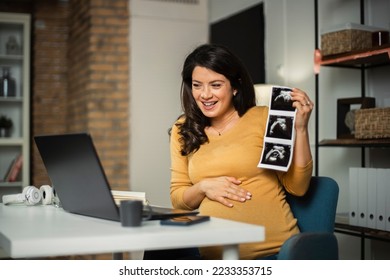Beautiful young pregnant woman looking at ultrasound pictures of her baby. Businesswoman having video call - Shutterstock ID 2233353715