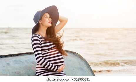 Beautiful young pregnant woman on the beach feels peace and tranquility
