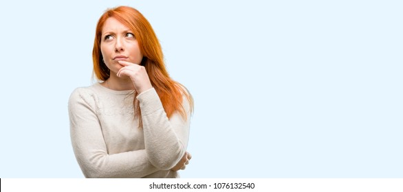 Beautiful Young Redhead Woman Doubt Expression, Confuse And Wonder Concept, Uncertain Future Isolated Over Blue Background