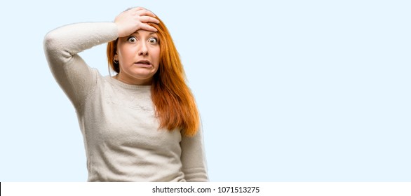 Beautiful young redhead woman terrified and nervous expressing anxiety and panic gesture, overwhelmed isolated over blue background