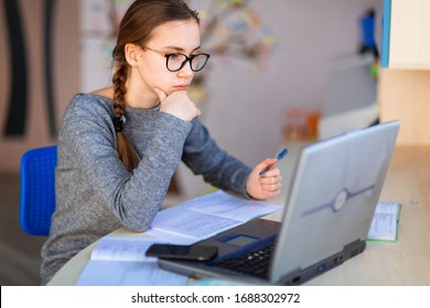 Beautiful Young School Girl Left-handed Working At Home In Her Room With A Laptop And Class Notes Studying In A Virtual Class. Distance Education, E-learning, Online Learning Concept During Quarantine