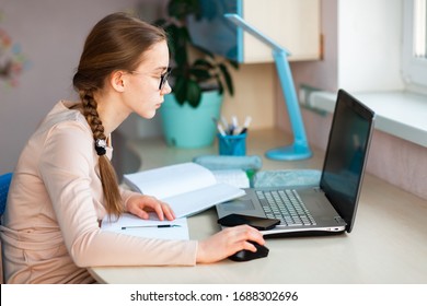 Beautiful Young School Girl Working At Home In Her Room With A Laptop And Class Notes Studying In A Virtual Class. Distance Education And E-learning, Online Learning Concept During Quarantine