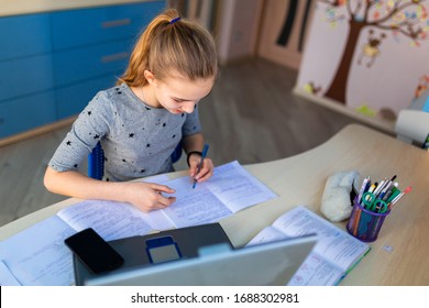 Beautiful Young School Girl Working At Home In Her Room With A Laptop And Class Notes Studying In A Virtual Class. Distance Education And E-learning, Online Learning Concept During Quarantine
