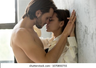 Beautiful Young Sensual Couple Holding Hands Leaning On Wall, Loving Millennial Affectionate  Man And Woman Getting Closer To Kiss Each Other Teasing Enjoying Tenderness And Intimacy, Feeling Desire