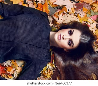 Beautiful Young Sexy Brunette Girl With Long Silky Hair Evening Makeup Perfect Figure Dressed Stylish Fashion Black Silk Pants Suit Blouse Lying Golden Autumn Leaves Collection Catalog Cosmetic Fall