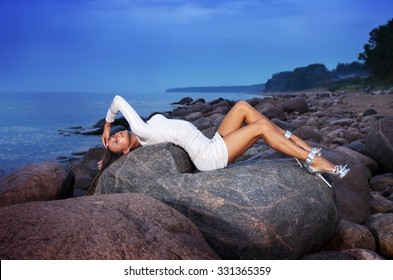 beautiful young sexy girl lying down on a rock at the water
