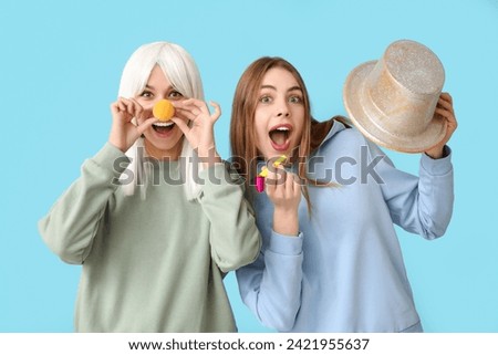 Beautiful young shocked women in funny disguise on blue background. April Fools Day celebration