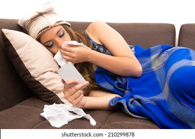 Beautiful Young Sick Girl Lying Down With A Cold Blowing Her Nose And Checking  Her Phone