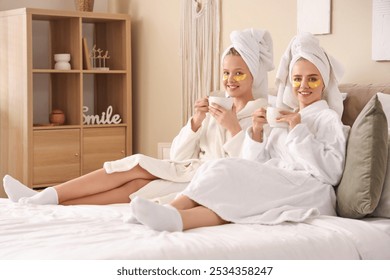 Beautiful young sisters after shower drinking tea in bedroom - Powered by Shutterstock