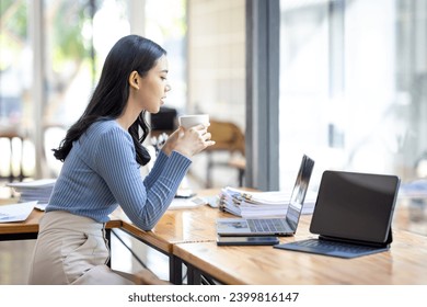 Beautiful young smiling Asian businesswoman working on laptop and drinking coffee, Asia businesswoman working document finance and calculator in her office.
 - Powered by Shutterstock