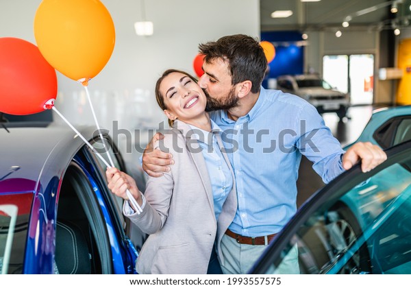 Beautiful young smiling couple in car showroom happy\
because of buying a new\
car.
