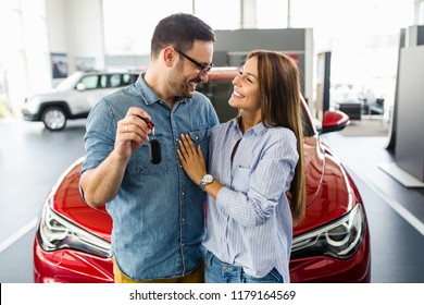 Beautiful young smiling couple holding a key of their new car.