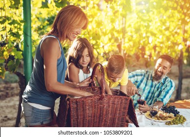Beautiful young smiling family of four with dog having picnic at a vineyard.