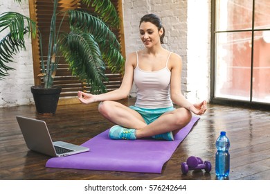 Beautiful Young Smiling Sport Woman Doing Yoga At Home With Laptop.