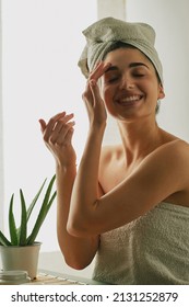 Beautiful Young Smiling Woman Caring Her Face With Aloe Plant On A Relaxing Background