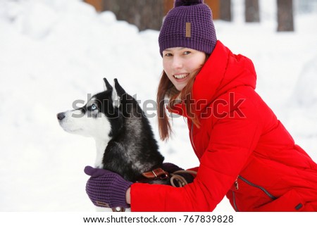 Beautiful young smiling woman walking in the Park in winter with a dog Husky
