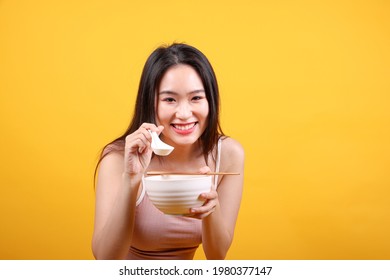 Beautiful Young South East Asian Woman Holding Chines Empty Chopstick Chinese Soup Spoon Bowl Utensil Pretend Acting Posing See Eat Taste Smell Feed Offer Satisfaction Yummy Yellow Orange Background