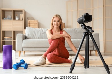 Beautiful young sport blogger recording video while training with roller and dumbbells at home - Powered by Shutterstock