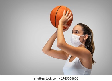 Beautiful young sport fitness woman basketball player using mask to protect herself and posing with basketball isolated over grey neutral background. - Powered by Shutterstock