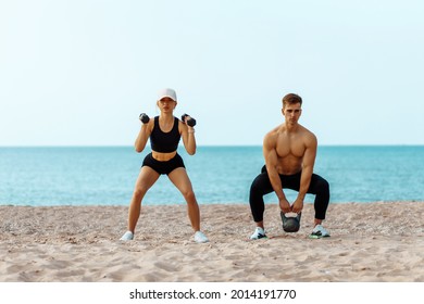 Beautiful young sportive couple exercising with dumbbells, doing sports exercises on the beach, Sports couple training with dumbbells, Muscular man and woman showing muscles - Powered by Shutterstock