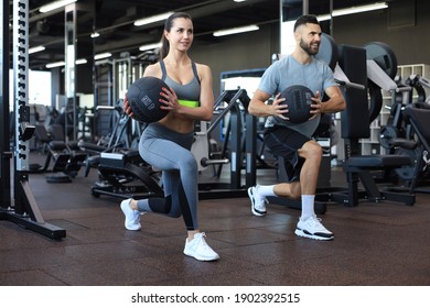 Beautiful young sports couple is working out with medicine ball in gym - Powered by Shutterstock